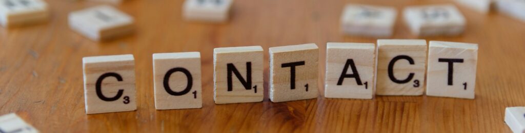 A wooden table topped with scrabble tiles spelling contact